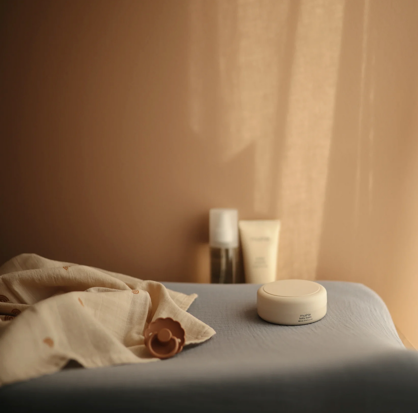 Baby balm fragrance free from Mushie, product laying on changing bed