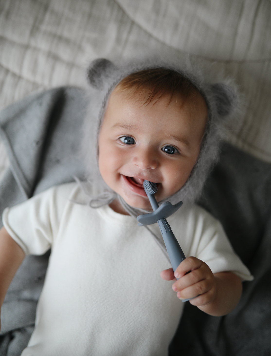 Star training toothbrush from mushie in Cambridge blue color hold by baby